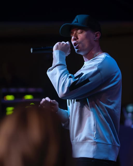 Leon Budrow performing with a microphone in a blue-lit live setting