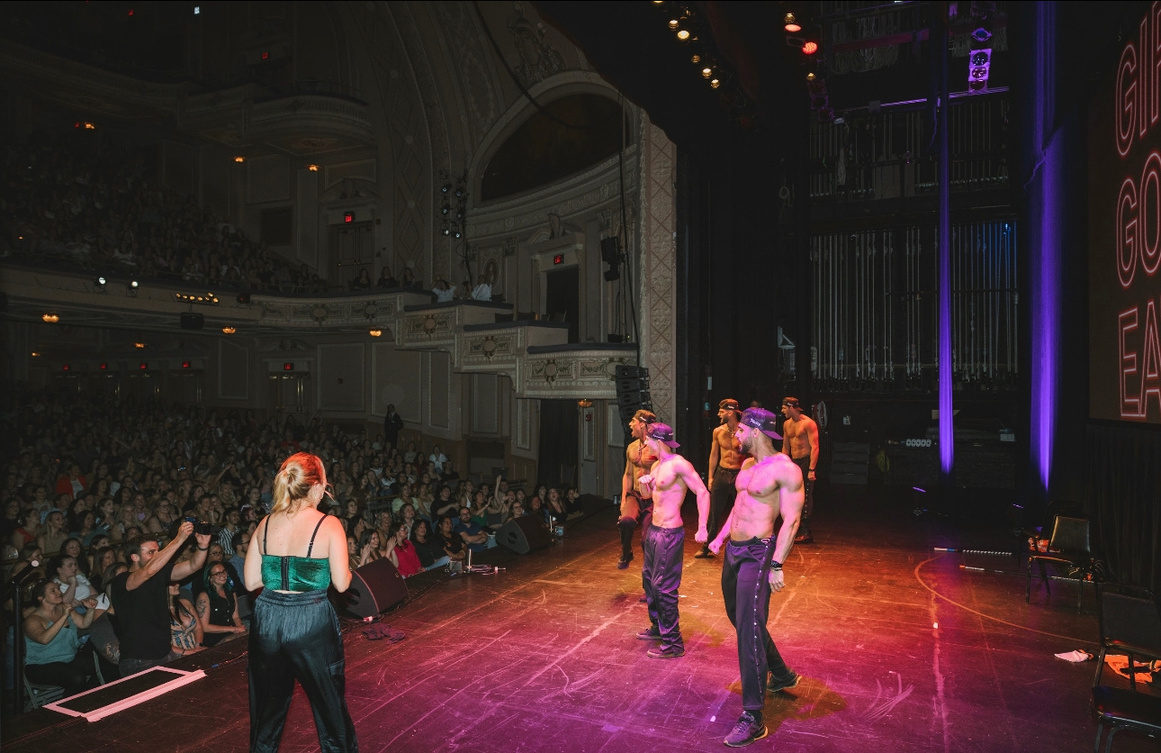 Live entertainers on a theatre stage before a large audience